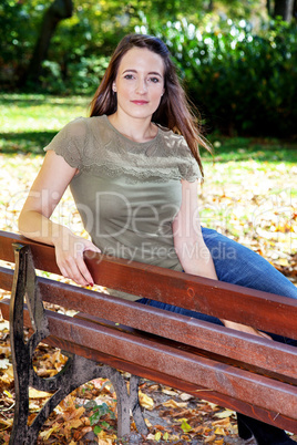 Woman sitting on park bench in autumn