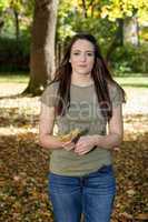 Woman walking in autumnal park and collect leaves