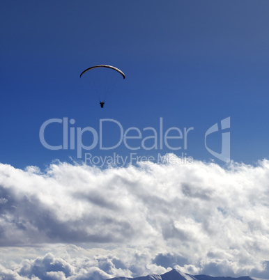 Silhouette of paraglider and blue sun sky