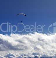 Silhouette of paraglider and blue sun sky