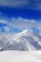 Off-piste slope and blue sky with clouds at sunny day
