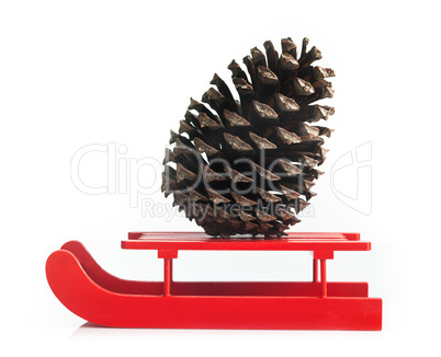 Wooden red sled with brown pine cone