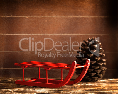 Wooden red sled with brown pine cone