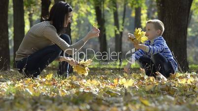 little boy and his mom collecting leaves in the park