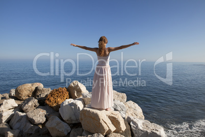 young woman at the sea standing on rock
