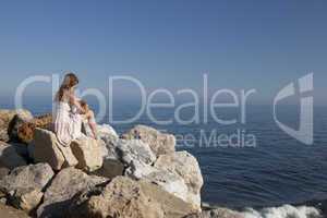 at the sea young woman sitting on rock