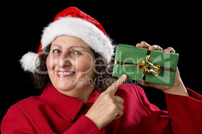 Smiling Mature Woman Pointing at Wrapped Xmas Gift.
