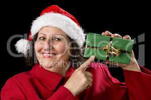 Smiling Mature Woman Pointing at Wrapped Xmas Gift.