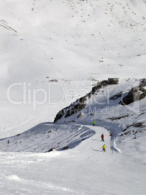 Snowboarders and skiers on ski slope at sun day