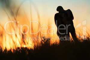 silhouette of a young couple kissing at sunset