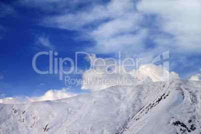 Off-piste slope at evening and sky with clouds