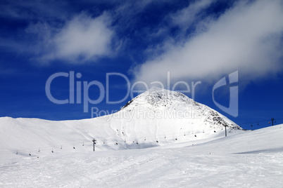 Chair-lift and ski slope at sun wind day