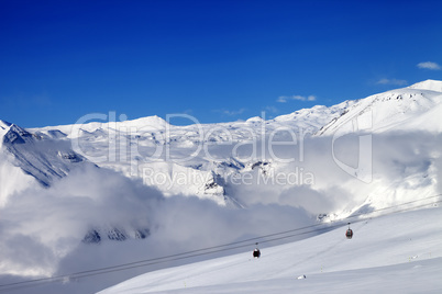 Off-piste snowy slope and cable car at sun day