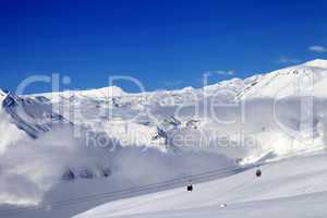 Off-piste snowy slope and cable car at sun day