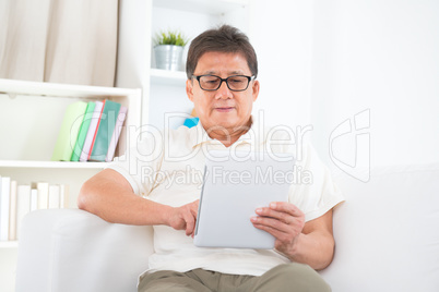Mature Asian man using tablet pc