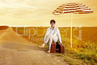 Woman sitting by the roadside on suitcases