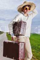 Woman with straw hat and sunglasses wearing holiday suitcase