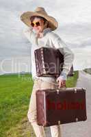 Woman with straw hat and sunglasses wearing holiday suitcase