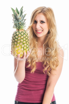 Frau hält eine Ananas und zieht eine Grimasse