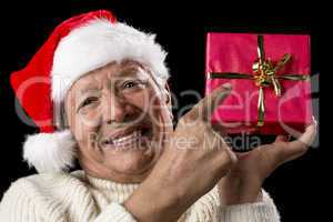 Male Senior Pointing At Red Wrapped Christmas Gift