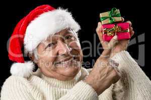 Smiling Senior Pointing At Two Wrapped Xmas Gifts