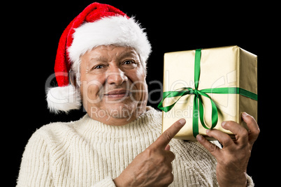 Male Senior With Santa Cap Pointing At Golden Gift