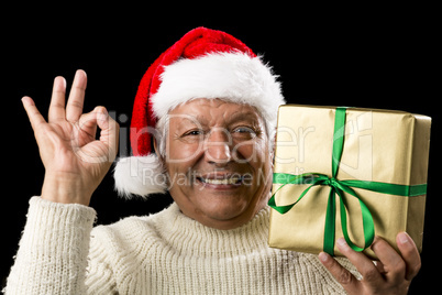 Grinning Male Senior With Gift Gesturing OK Sign