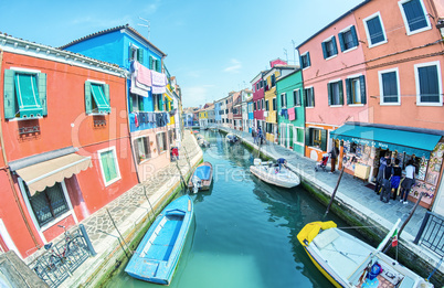 BURANO, ITALY - APRIL 8, 2014: Tourists enjoy colourful city bui