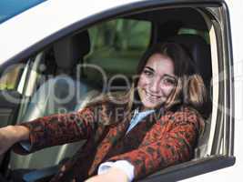 Young pretty smiling girl sitting behind the wheel of a car