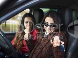 Two cute young smiling girl sitting in a car