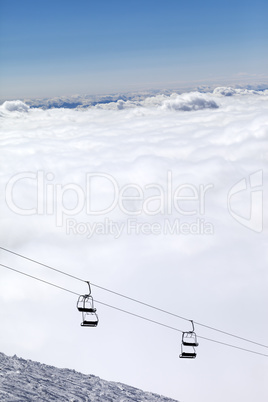 Ski slope, chair-lift and mountains under clouds