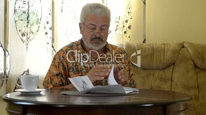 Senior man sitting at table working out bills