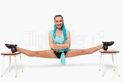 A girl sits in a pose of twine between two stools