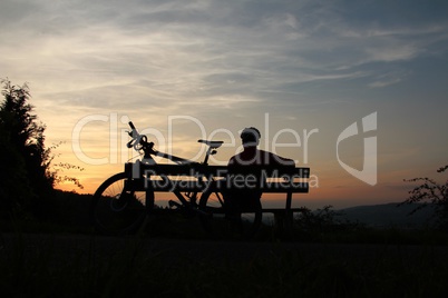Mountainbiker macht Pause bei Sonnenuntergang