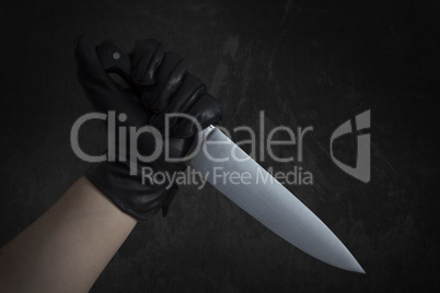 Hand in leather gloves holding knife