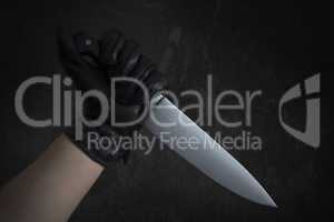 Hand in leather gloves holding knife
