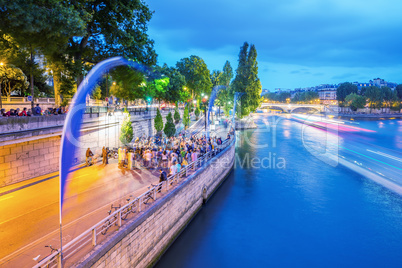 PARIS - JUNE 13, 2014: Tourists along Seine river at dusk. More