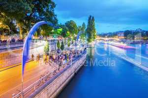 PARIS - JUNE 13, 2014: Tourists along Seine river at dusk. More