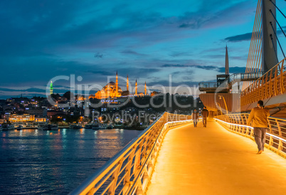 Istanbul at dusk. Walking on New Galata Bridge with Mosque and G