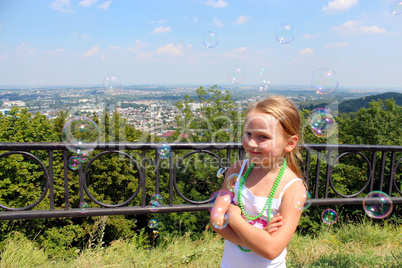 little girl with soap bubbles out of city