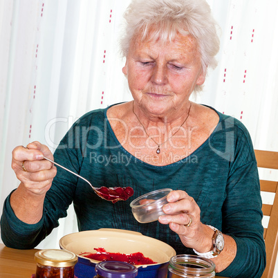 Senior woman filling homemade jam in the glass