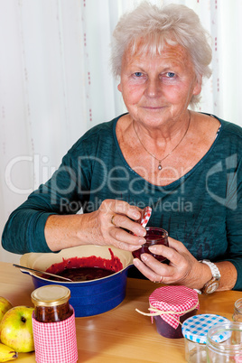 Senior woman filling homemade jam in the glass