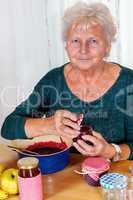 Senior woman filling homemade jam in the glass