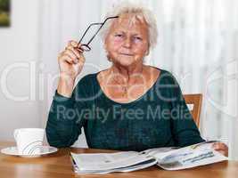 Elderly woman with cup looks up from reading