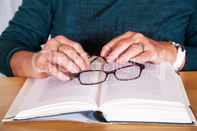 Hands of an elderly woman lying on the book