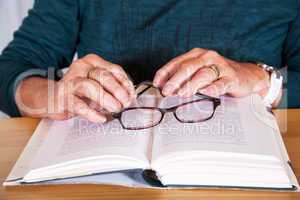 Hands of an elderly woman lying on the book