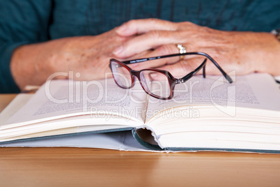 Hands of an elderly woman lying on the book