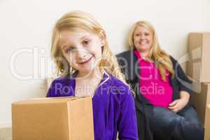 Young Mother and Daughter In Empty Room With Moving Boxes