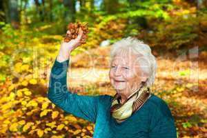 Senior woman poses with autumn leaves in the park