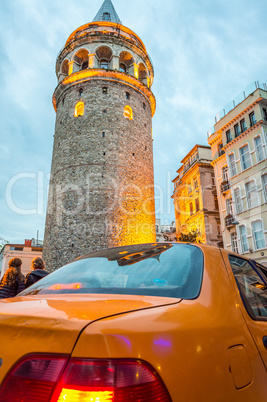 Taksi under Galata Tower at dusk. Vintage street scene in Istanb